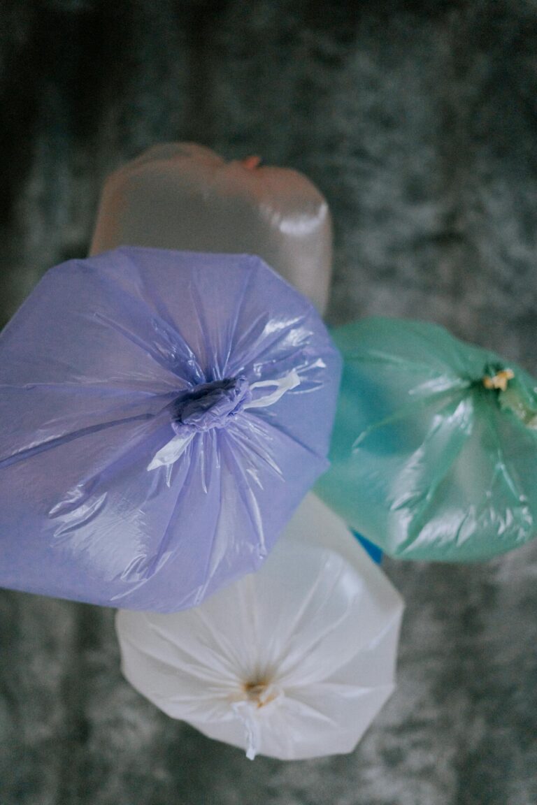 Overhead shot of assorted colored plastic bags tied and placed on dark background. Environmental focus.